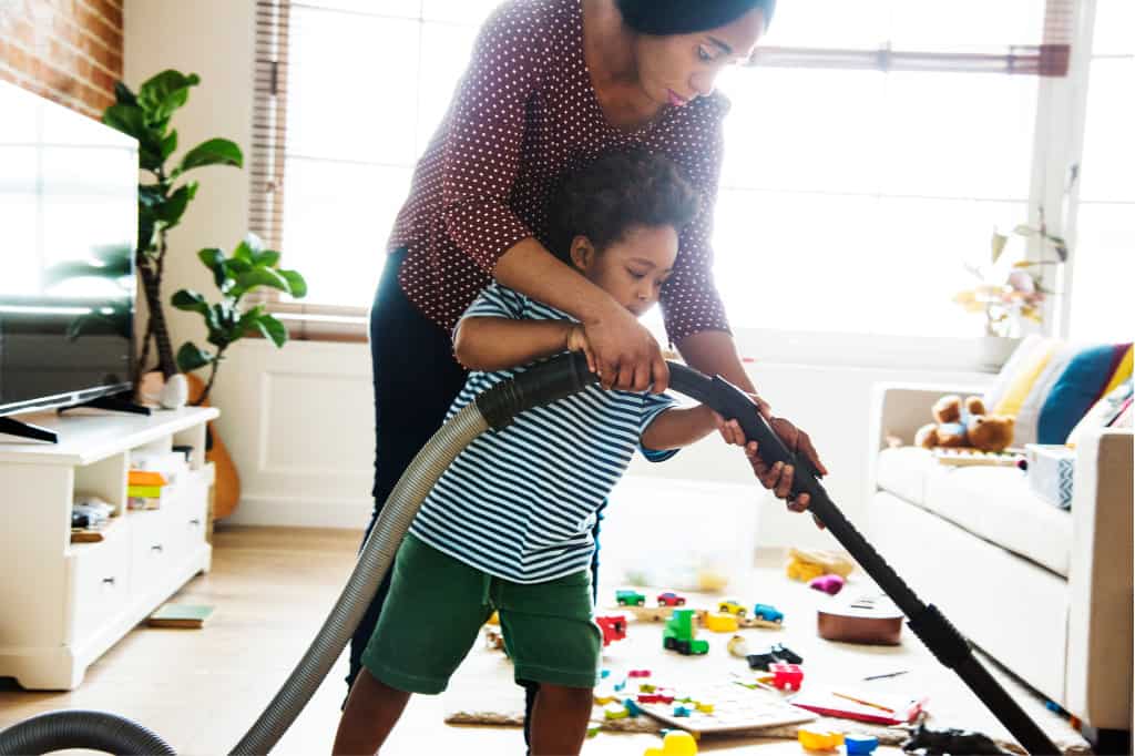 If you want to know how to get kids to do chores, an important part is to explicitly train them. This mom is training her son how to vacuum the floor.