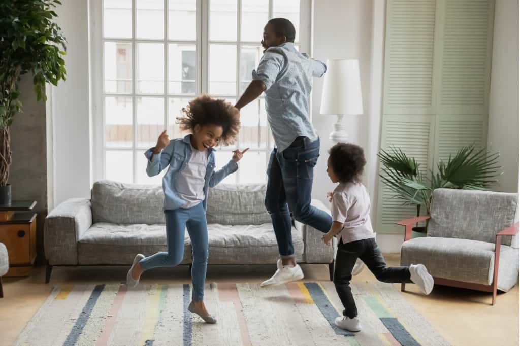 Make cleaning fun for kids by having a dance party. This dad is dancing with his kids.