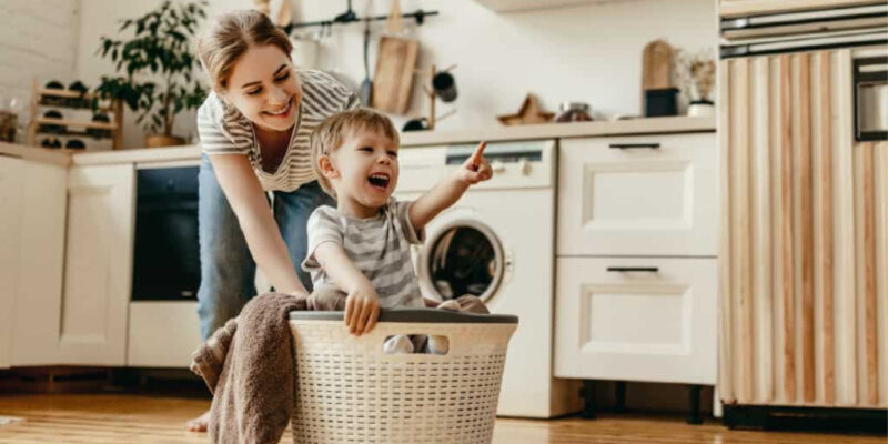 It's important to make cleaning fun for kids. This mom is pushing her son in the laundry basket.