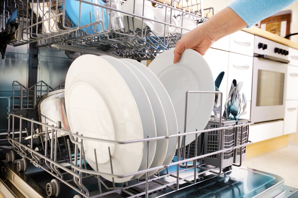 If you want to know how to always have a clean house, one way is to deal with dishes immediately. This woman is emptying the dishwasher.