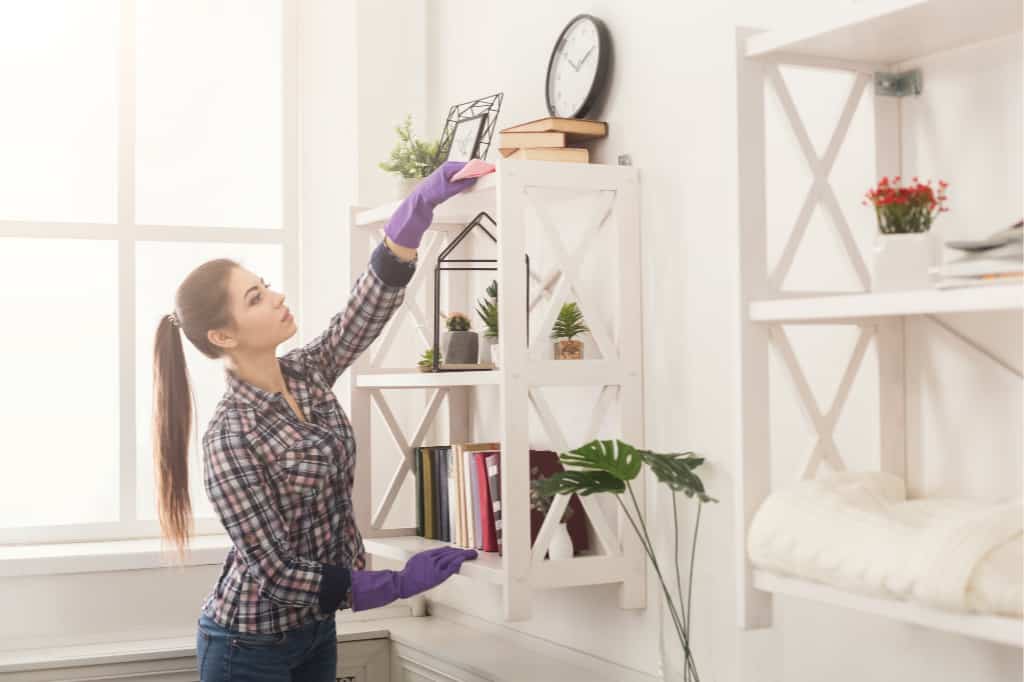 Automating your life by creating a cleaning schedule can save you a lot of time. This woman is dusting her house.