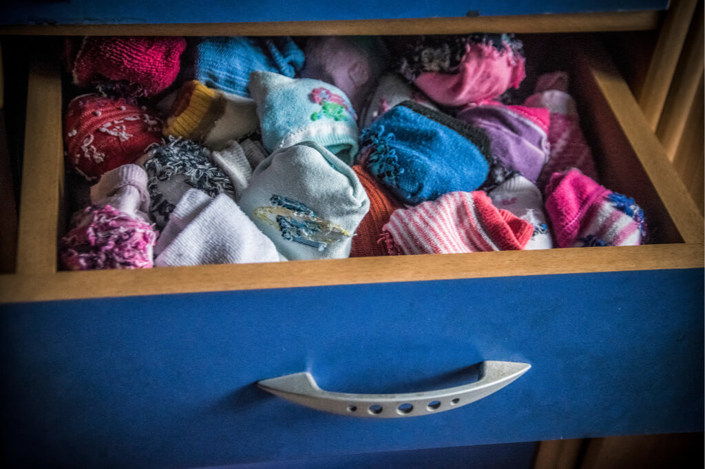 A variety of colorful socks are in a drawer. Having same colored socks makes laundry faster.