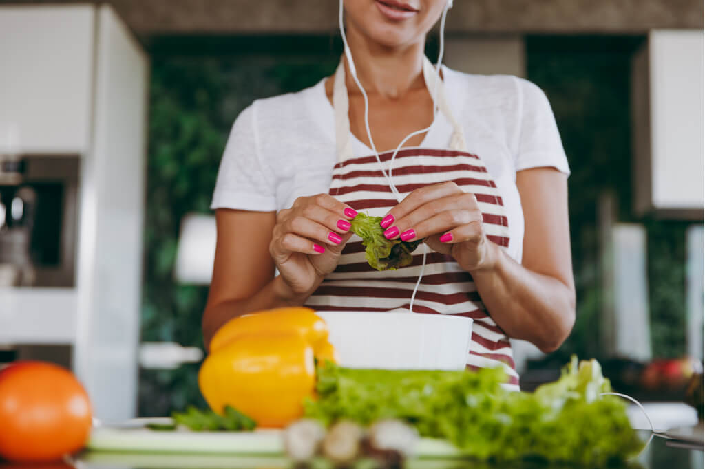 Highly productive people make the most of idle time. This woman is listening to an audio book while she is preparing a meal.