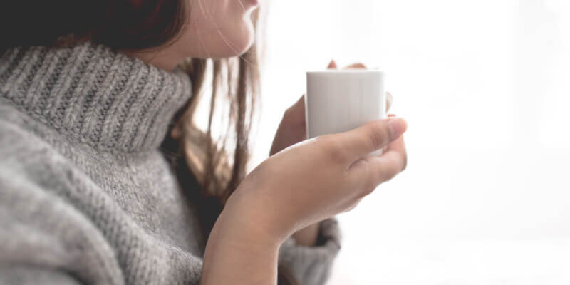 woman is relaxing and drinking a cup of hot tea as part of her stress-free morning routine.